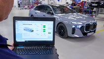 Engineer holds up laptop screen to camera showing battery efficacy with BMW i7 fitted with solid state batteries in background