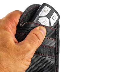 Hand holding a faraday pouch with car keys poking out of the top