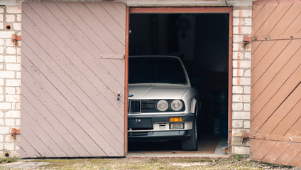 BMW peeping out of a garage, with one garage door open