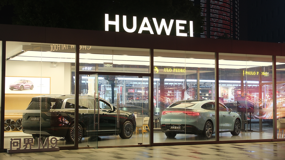 Nighttime shot of Huawei dealership in Wuhan, China with a couple of cars on display