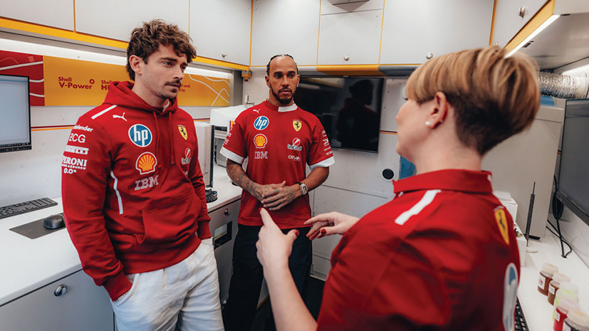 Scuderia Ferrari HP F1 drivers Charles Leclerc and Lewis Hamilton talking to a member of the team in the Shell Track Lab