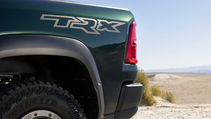 The rear quarter panel of a green Ram 1500 TRX shows the TRX logo above the rear wheel.
