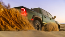 A green Ram 1500 TRX driving through sand with the rear lights illuminated.