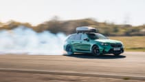 A green BMW, creating a cloud of white smoke behind it as it drives.