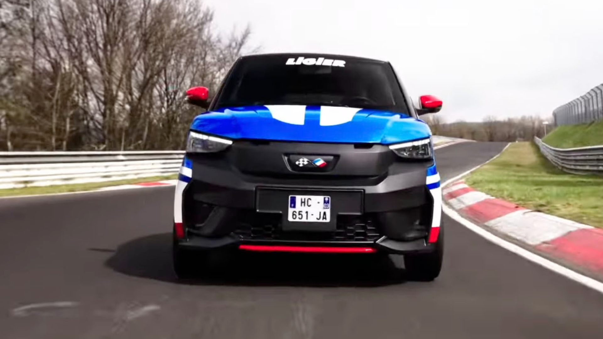 A blue and white Ligier car with the number 26 on the side races on a track.