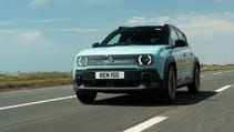 A pastel blue Renault 4 E-Tech electric car drives on an open road under a clear sky. The license plate reads "REN 150"