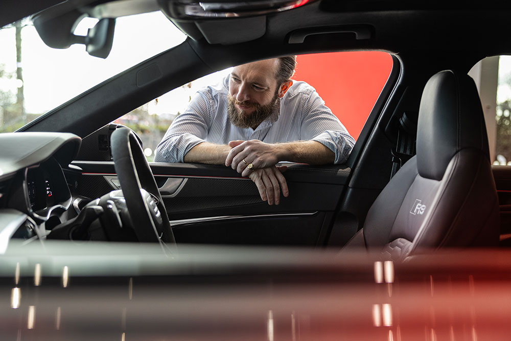 A man looking through the driver's window of an Audi RS